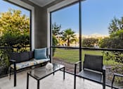 Thumbnail 21 of 22 - A balcony with a sofa, table, and chairs overlooking a garden.