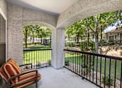 Thumbnail 17 of 22 - A patio with a striped chair and a view of a fenced yard.