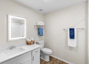 Thumbnail 21 of 23 - A white bathroom with a toilet, sink, mirror, and towel rack.