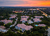 Thumbnail 18 of 22 - A sunset view of a residential area with houses and parked cars.