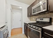 Thumbnail 24 of 28 - A modern kitchen with a stove top oven and microwave above it.