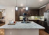 Thumbnail 26 of 32 - A kitchen with a marble countertop and stainless steel appliances.