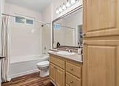 Thumbnail 27 of 30 - A bathroom with a wooden cabinet, a white toilet, and a white bathtub.
