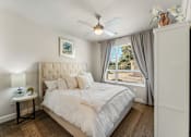 Thumbnail 29 of 32 - A bedroom with a large bed and a ceiling fan.