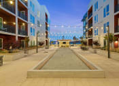Thumbnail 31 of 32 - Bocce ball and outdoor fireplace in a well-lit courtyard - La Via Apartments
