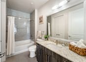Thumbnail 30 of 32 - A bathroom with a white toilet, a sink, and a bathtub with a shower curtain.