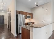 Thumbnail 34 of 42 - A kitchen with a granite countertop and stainless steel appliances.