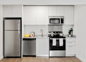 Thumbnail 3 of 29 - A modern kitchen with white cabinets and stainless steel appliances.