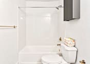 Thumbnail 10 of 29 - A white toilet sits next to a bathtub in a bathroom.