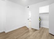 Thumbnail 16 of 29 - a bedroom with white walls and wood flooring and a door to a bathroom