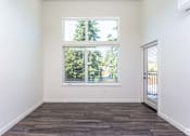 Thumbnail 15 of 25 - A room with a large window and wooden flooring. at Plisko Place, Port Orchard, WA