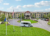 Thumbnail 1 of 45 - A white bus is parked in front of a building with a flag on a pole.