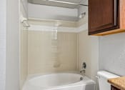 Thumbnail 58 of 64 - A white bathtub in a bathroom with a brown counter top.