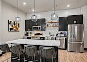 Thumbnail 15 of 64 - A modern kitchen with a white island and black cabinets.