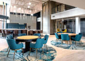 Thumbnail 12 of 75 - two circular tables with 6 chairs around each in an indoor kitchen at The Apex at CityPlace, Overland Park, 66210