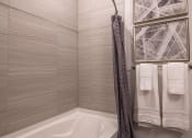 Thumbnail 41 of 75 - a tub with a shower curtain and towels in a bathroom at The Apex at CityPlace, Kansas