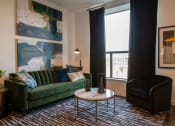 Thumbnail 31 of 75 - sitting area with a large green couch, small black chair, coffee table, and black curtains at The Apex at CityPlace, Overland Park, KS, 66210