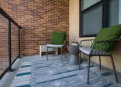 Thumbnail 33 of 75 - the balcony of an apartment with two chairs and a rug looking over a glass railing at The Apex at CityPlace, Kansas