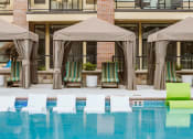 Thumbnail 6 of 75 - chaise lounge chairs under a canopy by an outdoor pool at The Apex at CityPlace, Overland Park, KS
