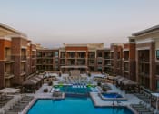 Thumbnail 57 of 75 - zoomed out aerial view of outdoor pool and chairs around it in the center yard of an apartment complex at The Apex at CityPlace, Overland Park, 66210