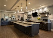 Thumbnail 26 of 34 - Community kitchen with granite counter tops and a tv at Aspen Ridge 55+ Active Adult Community