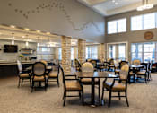 Thumbnail 25 of 34 - Dining hall with tables and chairs and a kitchen at Aspen Ridge 55+ Active Adult Community