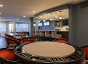 Thumbnail 24 of 34 - A clubhouse lounge with tables, chairs, and a bar top at Aspen Ridge 55+ Active Adult Community
