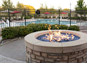 Thumbnail 34 of 34 - An outdoor fire pit in front of a swimming pool at Aspen Ridge 55+ Active Adult Community