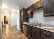 Thumbnail 17 of 34 - A kitchen with wooden cabinets and a stainless steel sink at Aspen Ridge 55+ Active Adult Community