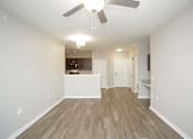 Thumbnail 15 of 34 - An empty living room and kitchen with a ceiling fan at Aspen Ridge 55+ Active Adult Community
