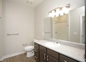 Thumbnail 14 of 34 - A bathroom with a large mirror and a sink and a toilet at Aspen Ridge 55+ Active Adult Community