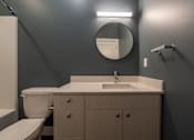 Thumbnail 9 of 18 - A bathroom with a toilet, sink, and mirror.