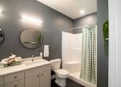 Thumbnail 6 of 18 - A bathroom with a white toilet and a green plant.