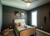 Thumbnail 4 of 18 - A bedroom with a bed, a ceiling fan, and two wall art pieces.