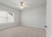 Thumbnail 5 of 36 - an empty bedroom with a ceiling fan and a window at Hillcrest Village, Springdale