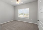 Thumbnail 2 of 36 - an empty bedroom with a large window and a ceiling fan at Hillcrest Village, Springdale, AR