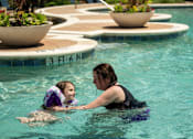 Thumbnail 66 of 67 - A woman and a child are swimming in a pool.