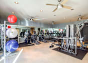 Thumbnail 15 of 23 - A gym with a variety of equipment including a weight bench, a rowing machine, and a treadmill.