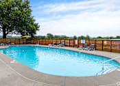 Thumbnail 16 of 19 - A rectangular pool with a concrete edge and a few chairs around it.