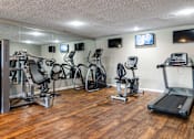 Thumbnail 18 of 19 - A gym with a variety of equipment including treadmills, stationary bikes, and weight machines.