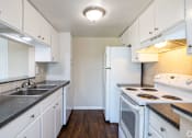 Thumbnail 2 of 19 - A kitchen with white cabinets and a black counter top.