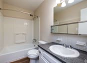 Thumbnail 11 of 19 - A white toilet sits next to a white bathtub in a bathroom.