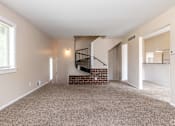 Thumbnail 8 of 19 - A room with a carpeted floor and a staircase with a metal railing.