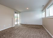 Thumbnail 10 of 19 - A spacious room with carpeted floor and sliding glass doors.