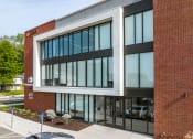 Thumbnail 1 of 15 - a brick building with large glass windows and a sidewalk