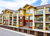 Thumbnail 43 of 59 - Apartment building with balconies and cars parked on the street.