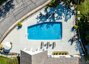 Thumbnail 4 of 44 - An aerial view of a swimming pool surrounded by a concrete patio and a building.