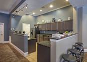 Thumbnail 12 of 50 - A kitchen with a bar area and stools.