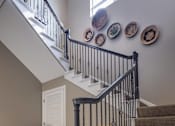 Thumbnail 23 of 50 - A staircase with a black railing and a yellow chair at the bottom.