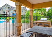 Thumbnail 18 of 50 - A patio with a table and chairs overlooking a pool.